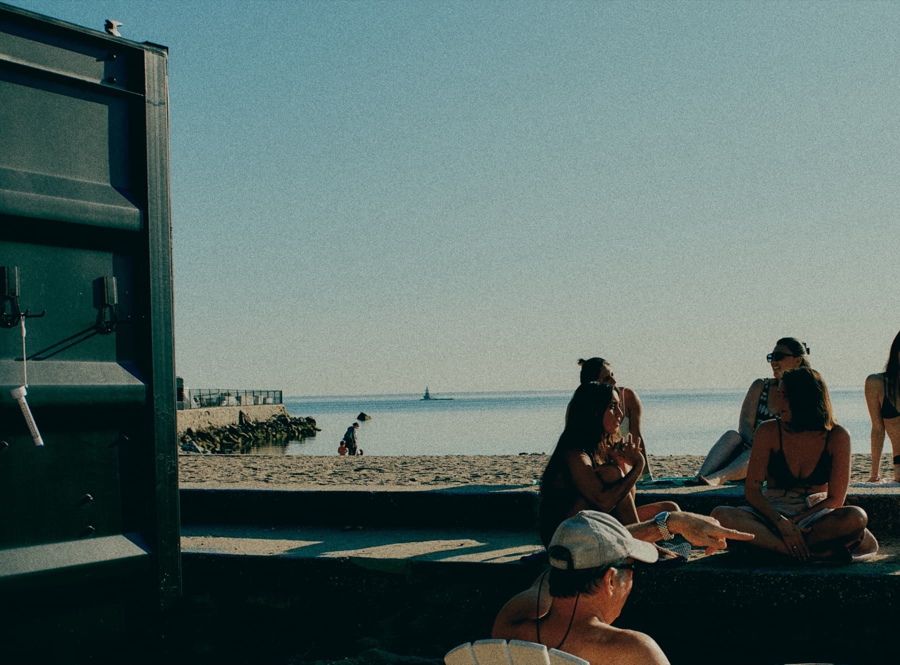 The TYDE HAUS sauna on the sand at Bayley Beach, people sitting outside it, the Sound behind.