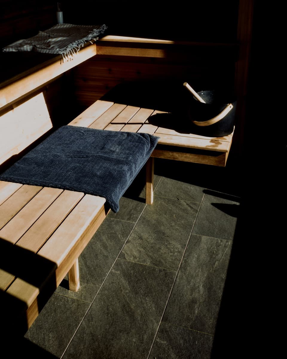 Cedar benches inside the sauna, a towel folded on the lower bench.