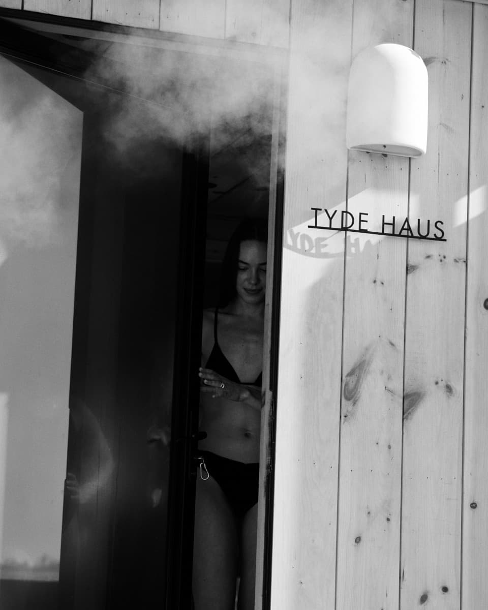 Steam pouring from the sauna door under the TYDE HAUS sign.