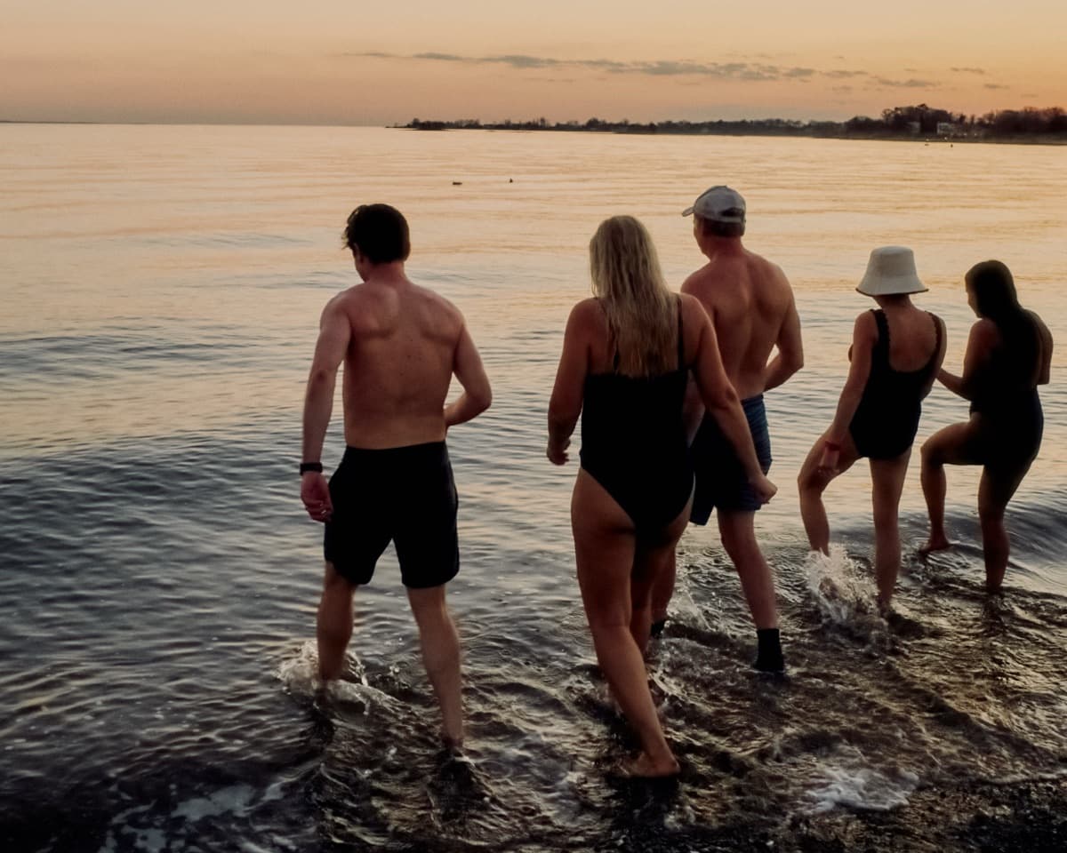 A group walking into the Sound at sunset after the heat.